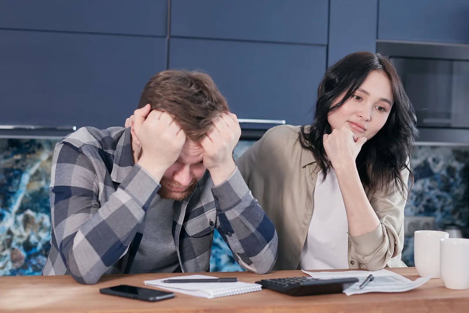 Hai vợ chồng ôm đầu bên bàn đầy giấy tờ